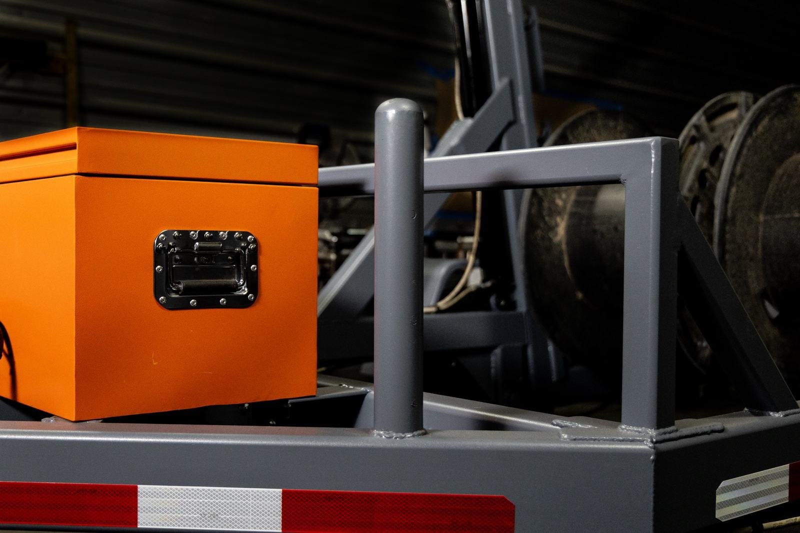 Weatherproof battery enclosure and cone holder on a reel trailer deck
